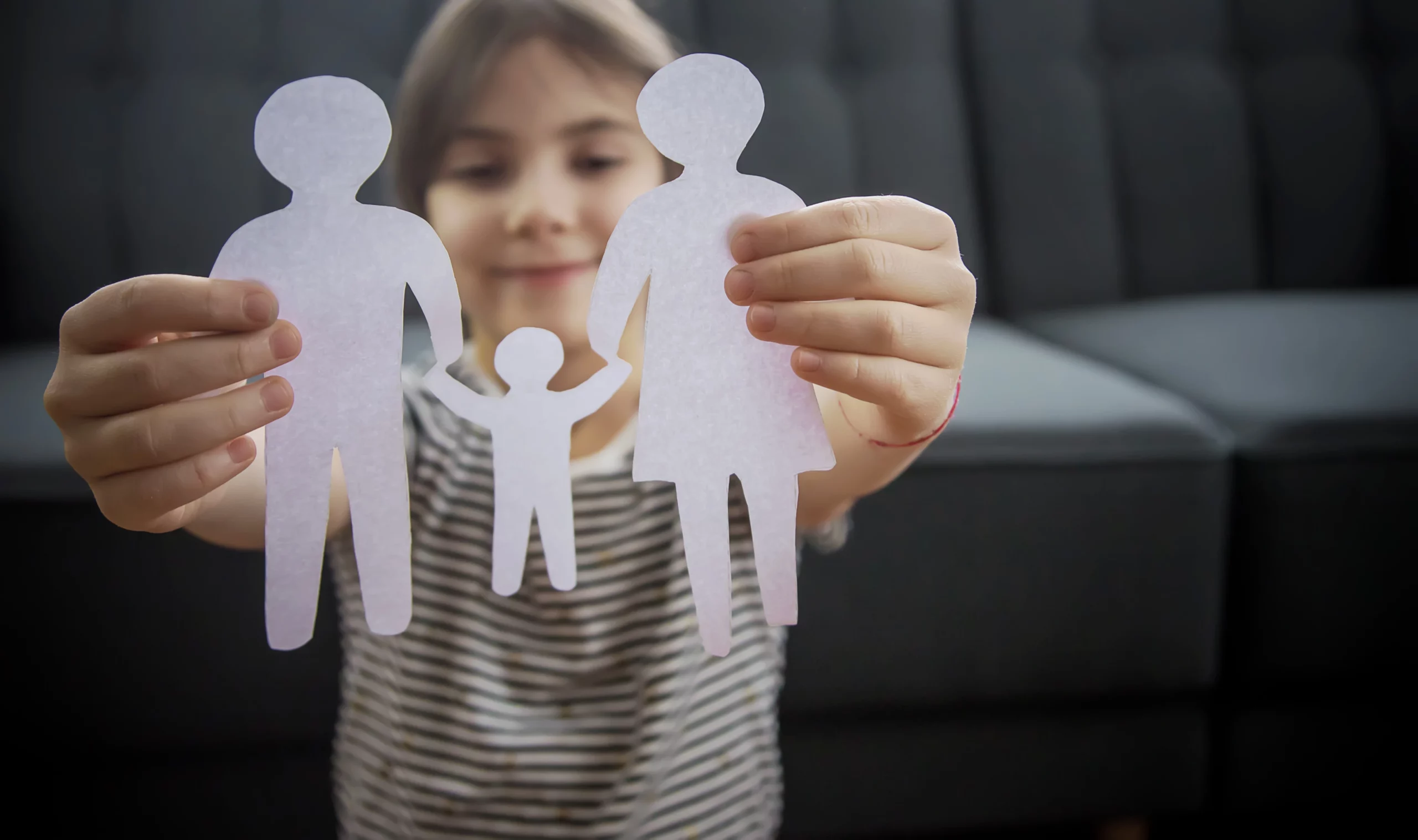 Smiling child holding paper cutout family, symbolizing child custody and parental choice in California.
