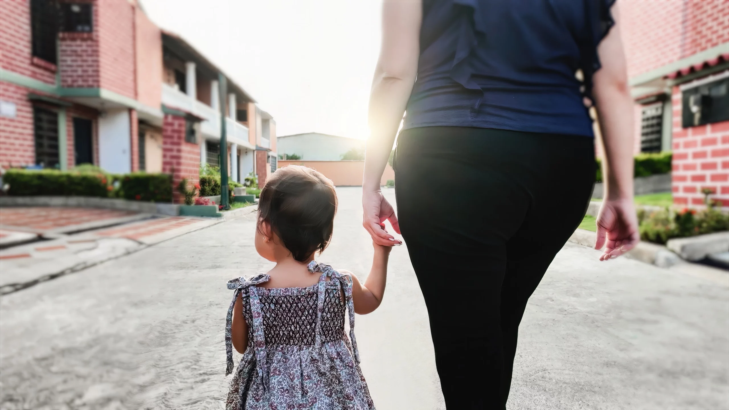 Child holding hands with parent on quiet street, symbolizing custody concerns after parental relocation in California.