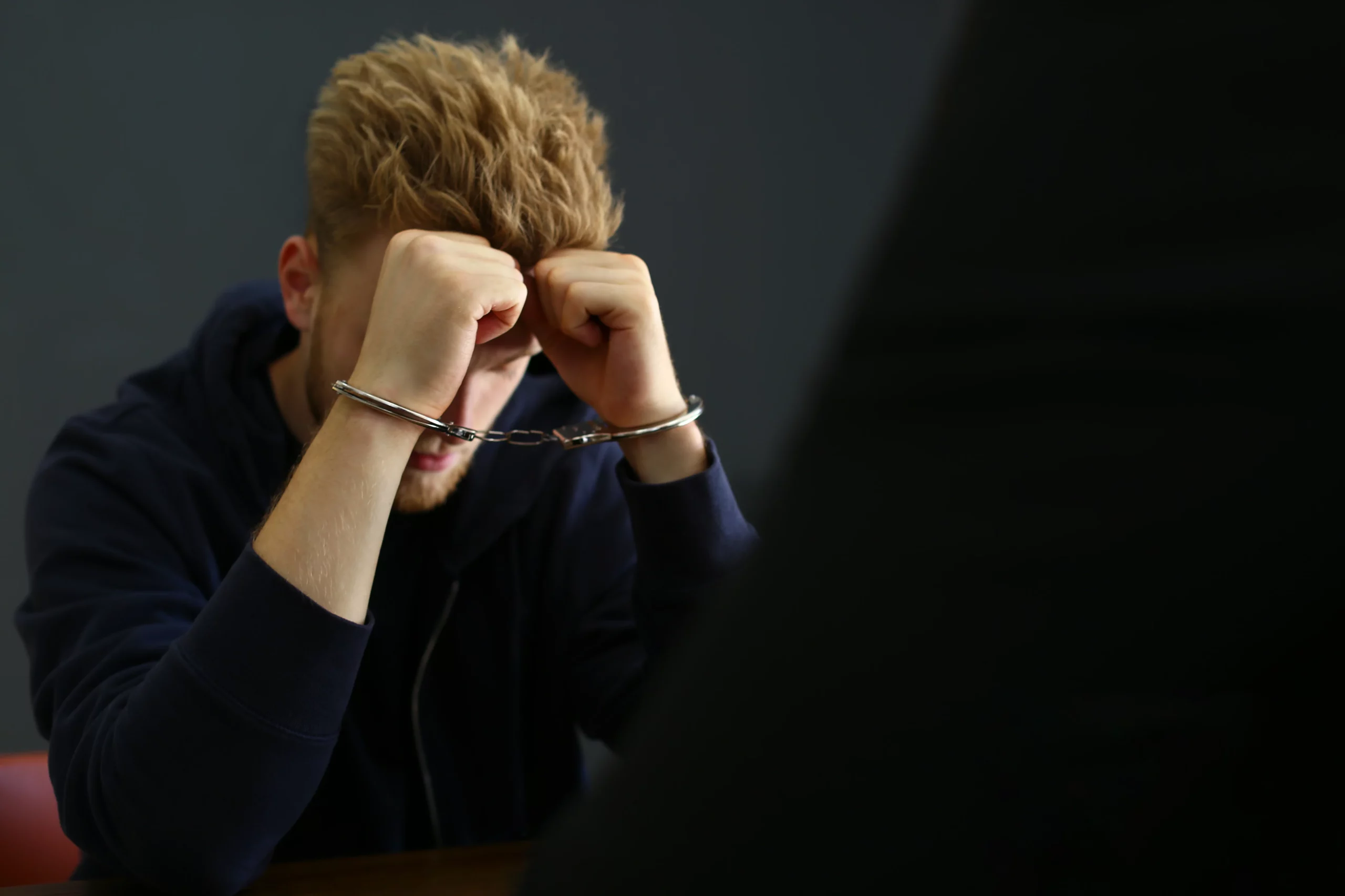 Handcuffed person sitting with head in hands, representing the stress of being falsely accused of a crime in California and the need to build a strong defense to prove innocence.