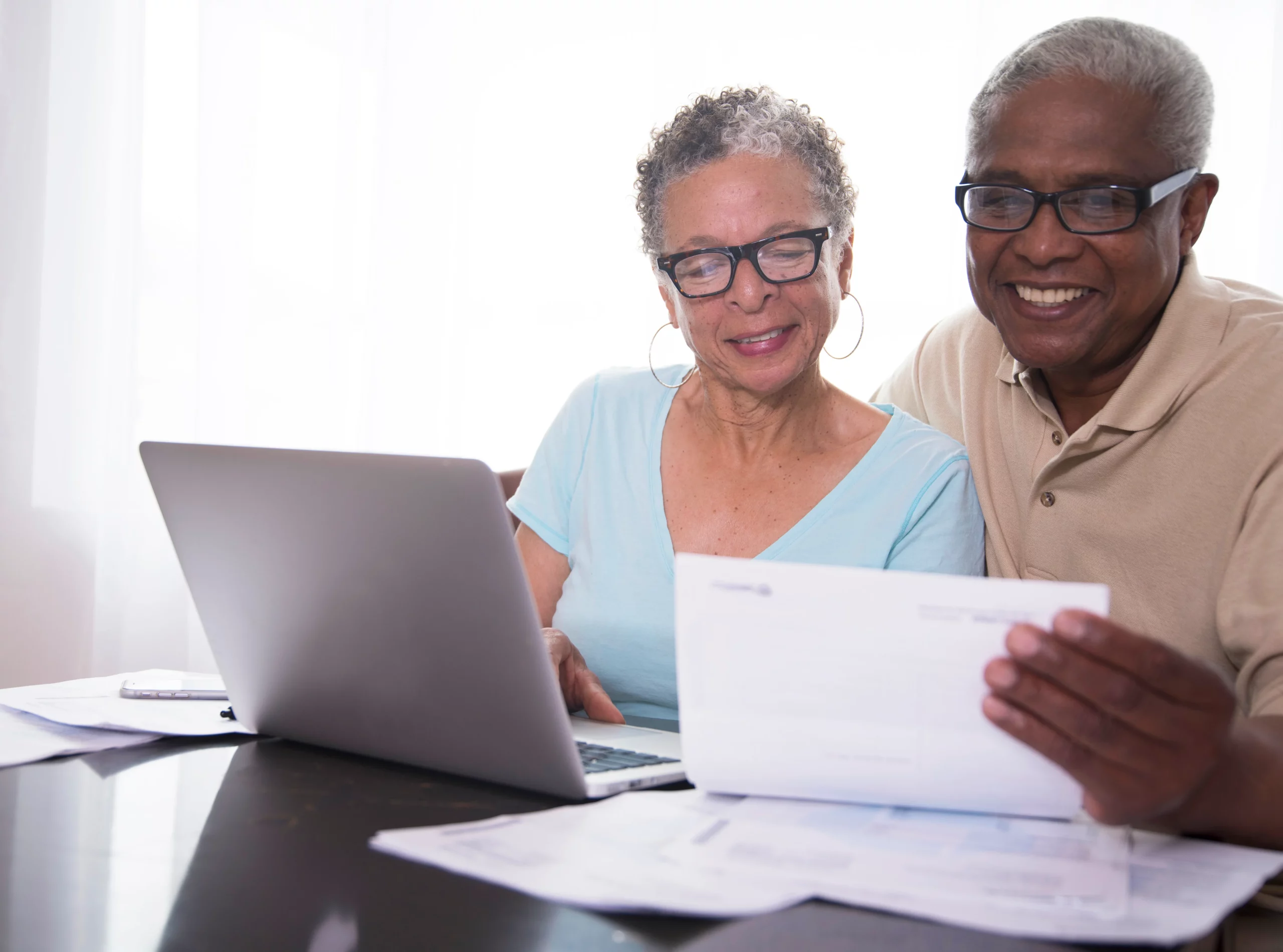 Smiling older couple reviewing finances together, representing how retirement accounts earned during marriage are divided equally in a California divorce under community property law.