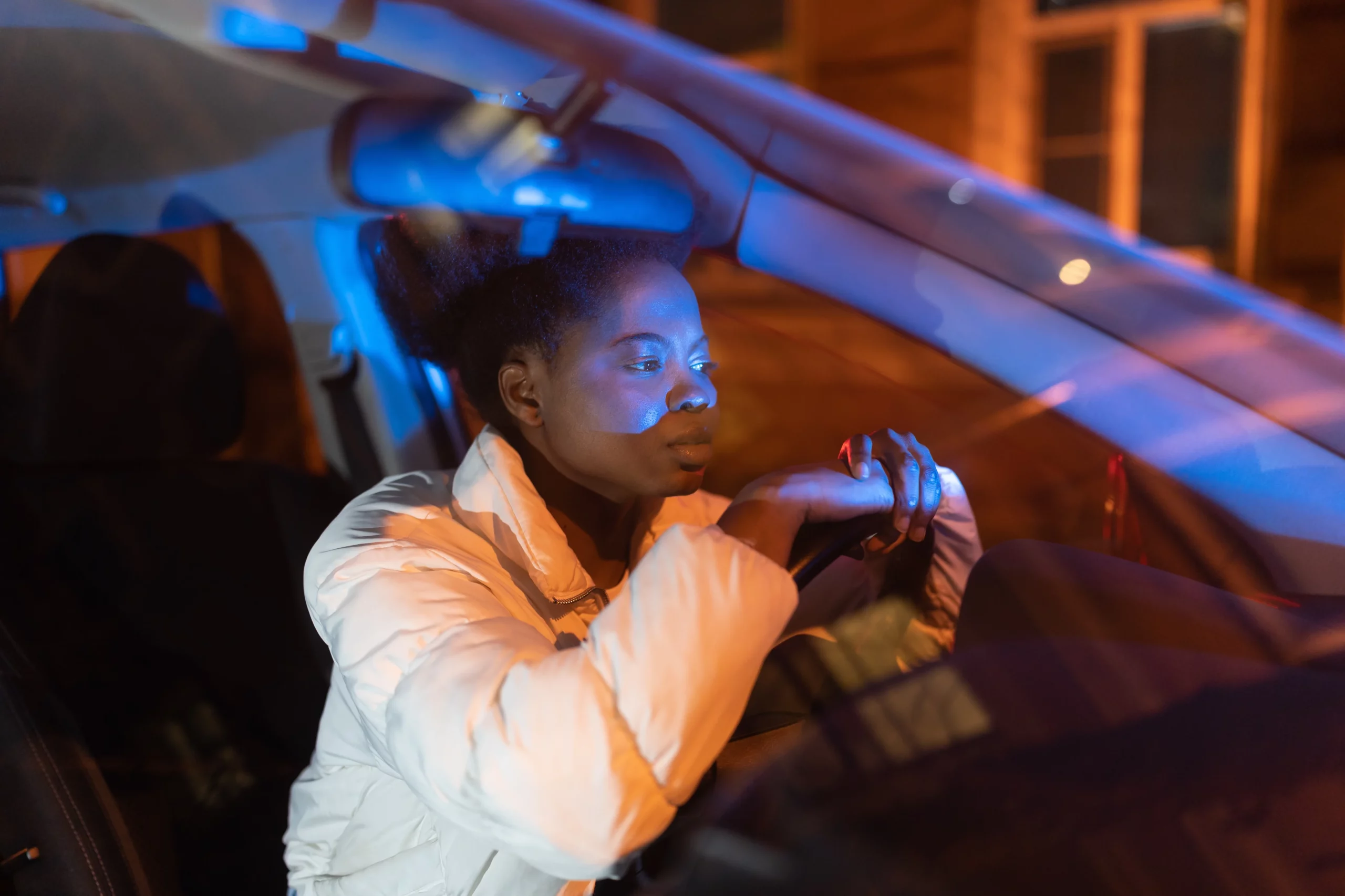 Woman sitting in a car illuminated by police lights during a traffic stop, representing California laws where officers cannot search a vehicle without consent, a warrant, or probable cause.
