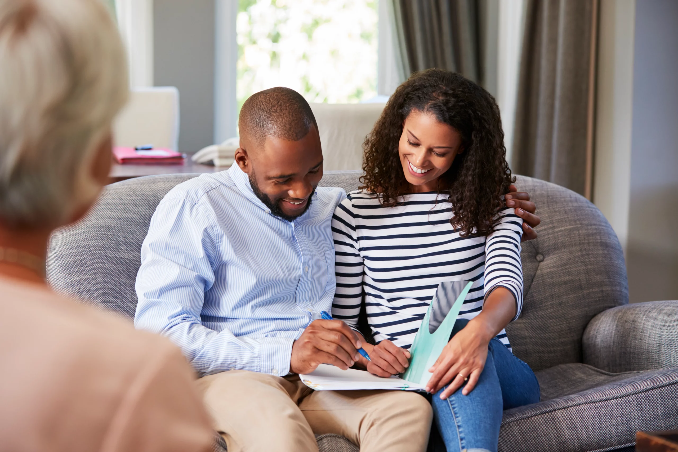 Couple meeting with a legal professional while signing documents, representing the process of setting up a living trust in California to avoid probate and protect family assets.