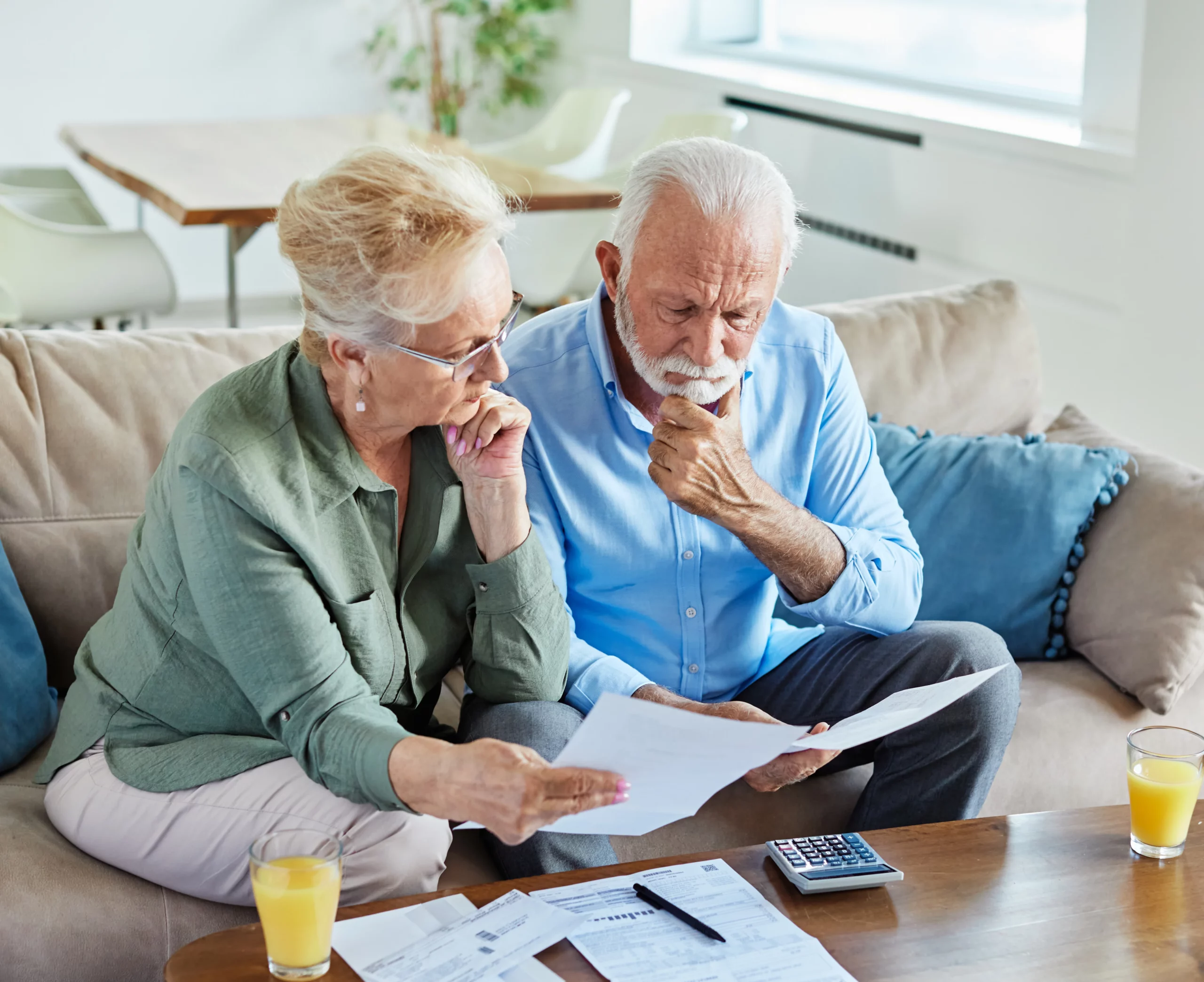Elderly couple reviewing estate planning documents and finances at home, discussing pour-over wills and protecting family assets as part of a California estate plan.