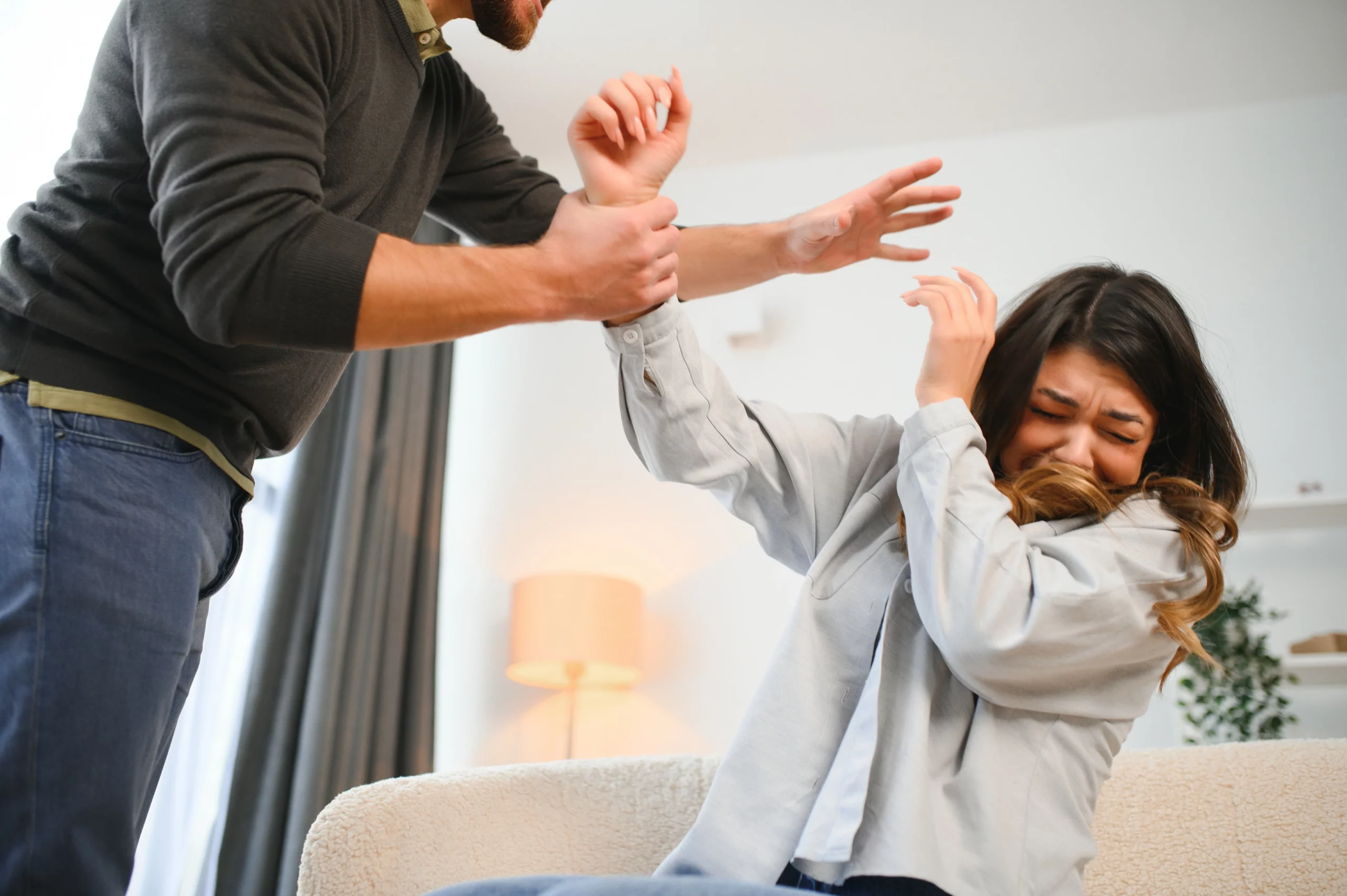 Woman reacting fearfully as a man grabs her hand, representing a domestic violence situation under California law.