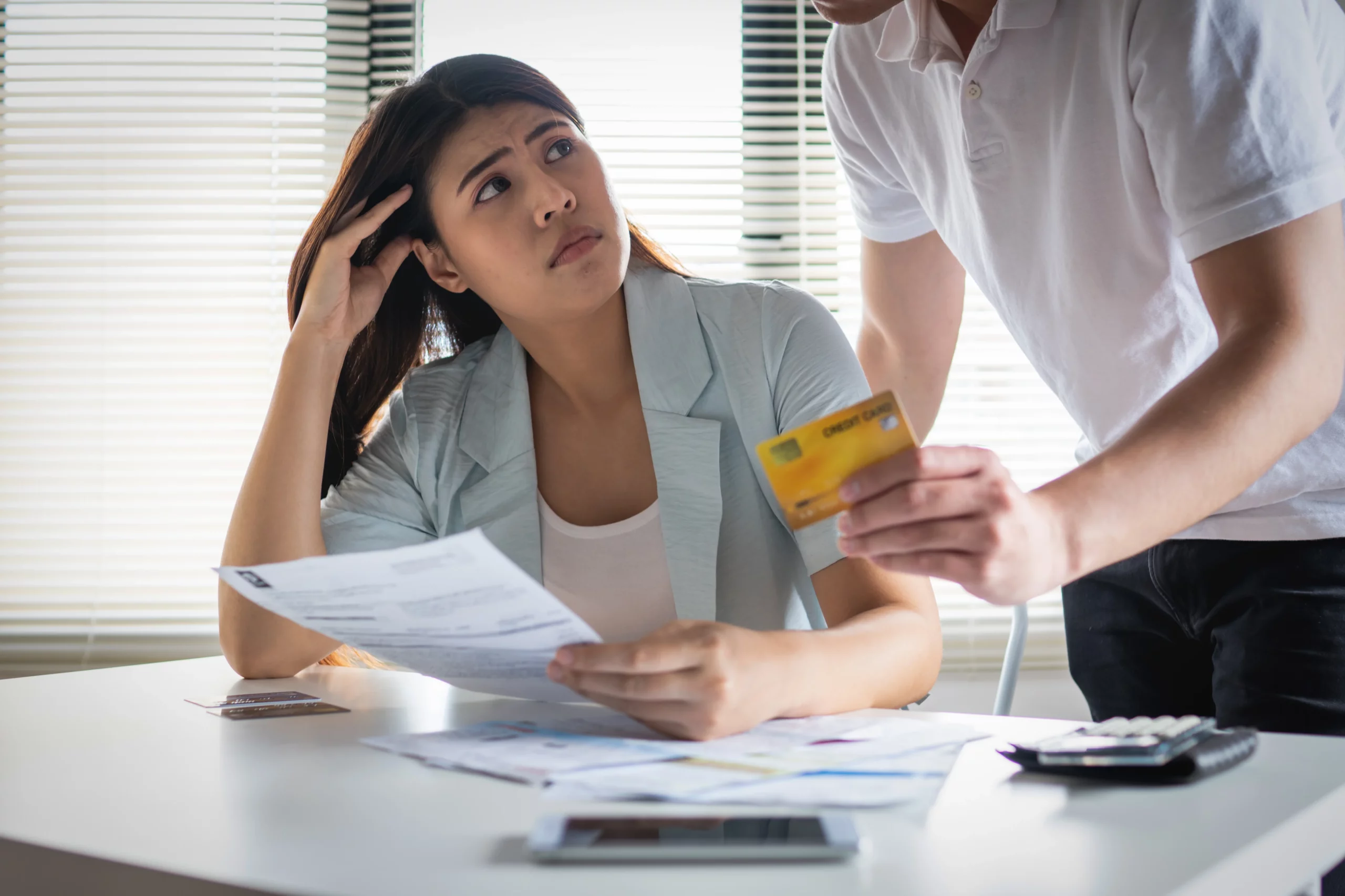 Couple reviewing bills and credit card debt during a stressful financial discussion, highlighting debt division and financial responsibilities in a California divorce.